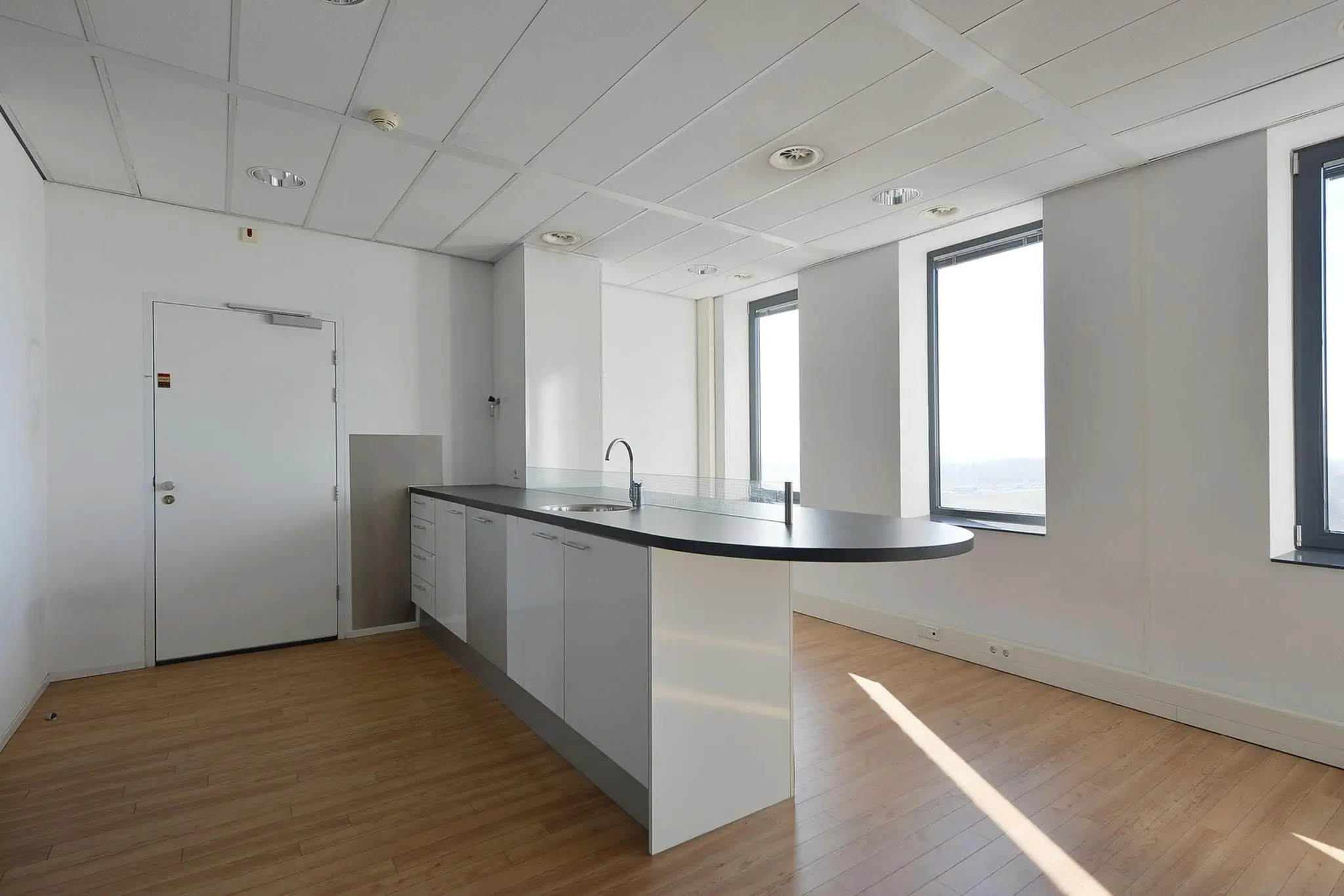 Moderne, lichte keukenruimte met kookeiland in een kantoorpand aan de Laan van Zuid Hoorn.